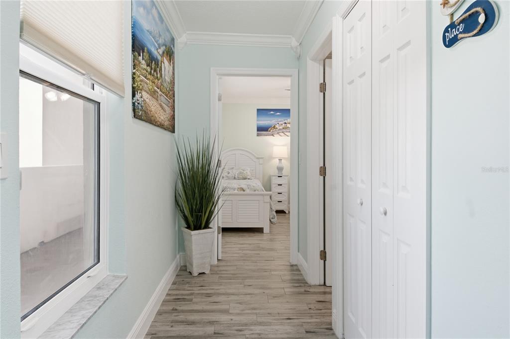 A hallway with light blue walls, wood-look tile flooring, and a view into a bedroom — 14800 GULF BOULEVARD UNIT 303, MADEIRA BEACH, FL