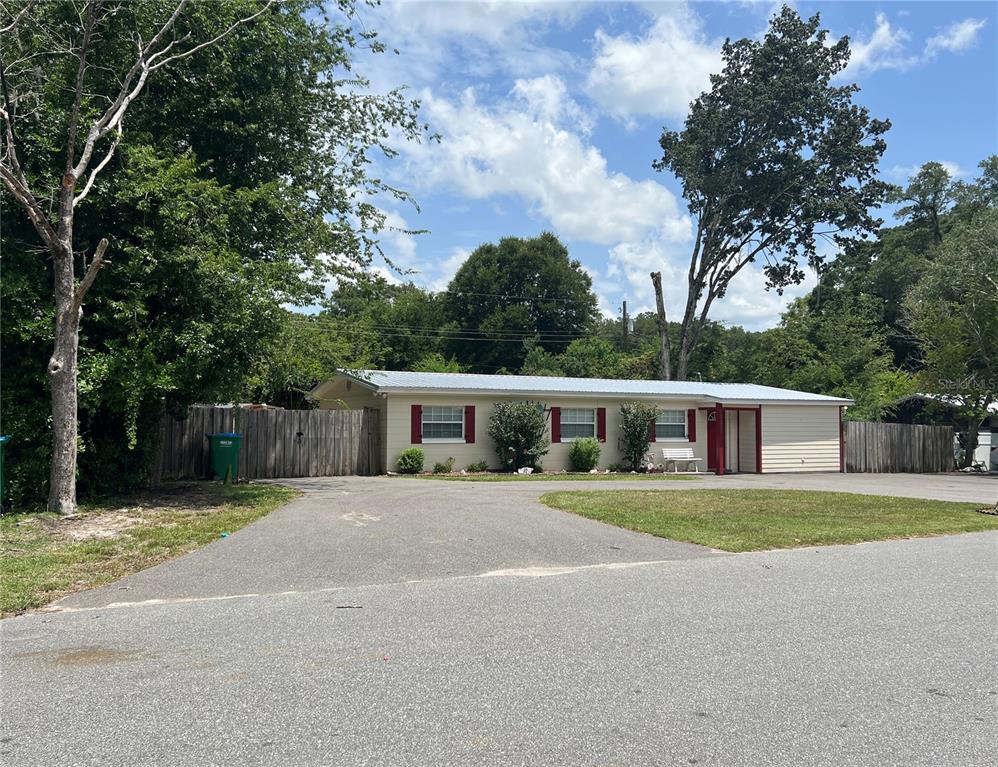 A single-story house with a metal roof, red shutters, and a large paved driveway — 17333 NW 243RD STREET, HIGH SPRINGS, FL