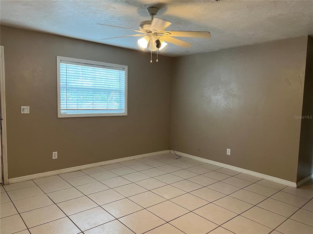 An empty room features tan walls, white tile flooring, and a ceiling fan — 17333 NW 243RD STREET, HIGH SPRINGS, FL