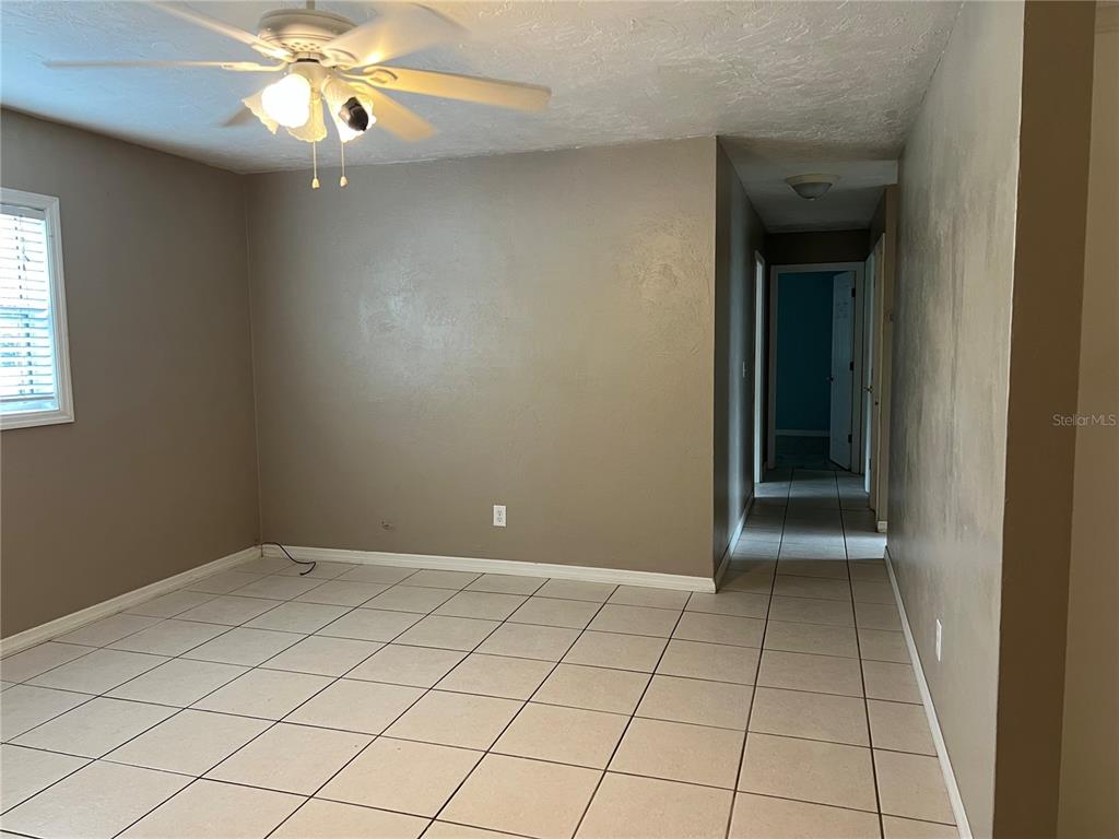 An empty room with tan walls, white baseboards, and light-colored square floor tiles — 17333 NW 243RD STREET, HIGH SPRINGS, FL
