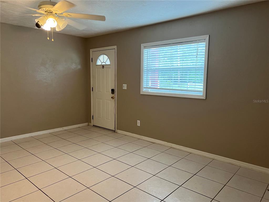 A room with light-colored tile flooring, a ceiling fan, a white door, and a window — 17333 NW 243RD STREET, HIGH SPRINGS, FL