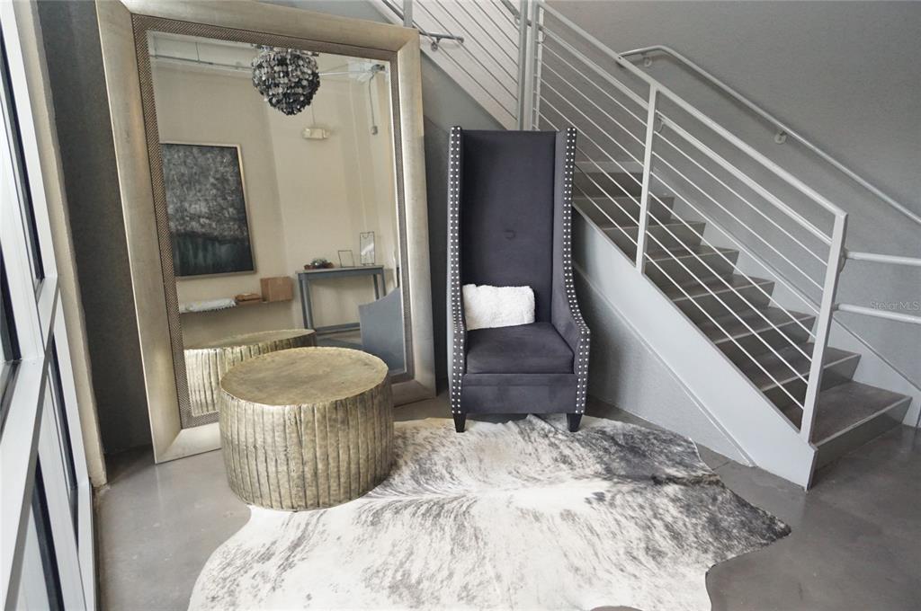 A high-backed gray chair sits on a cowhide rug next to a large floor mirror — 1501 W HORATIO STREET UNIT 111, TAMPA, FL