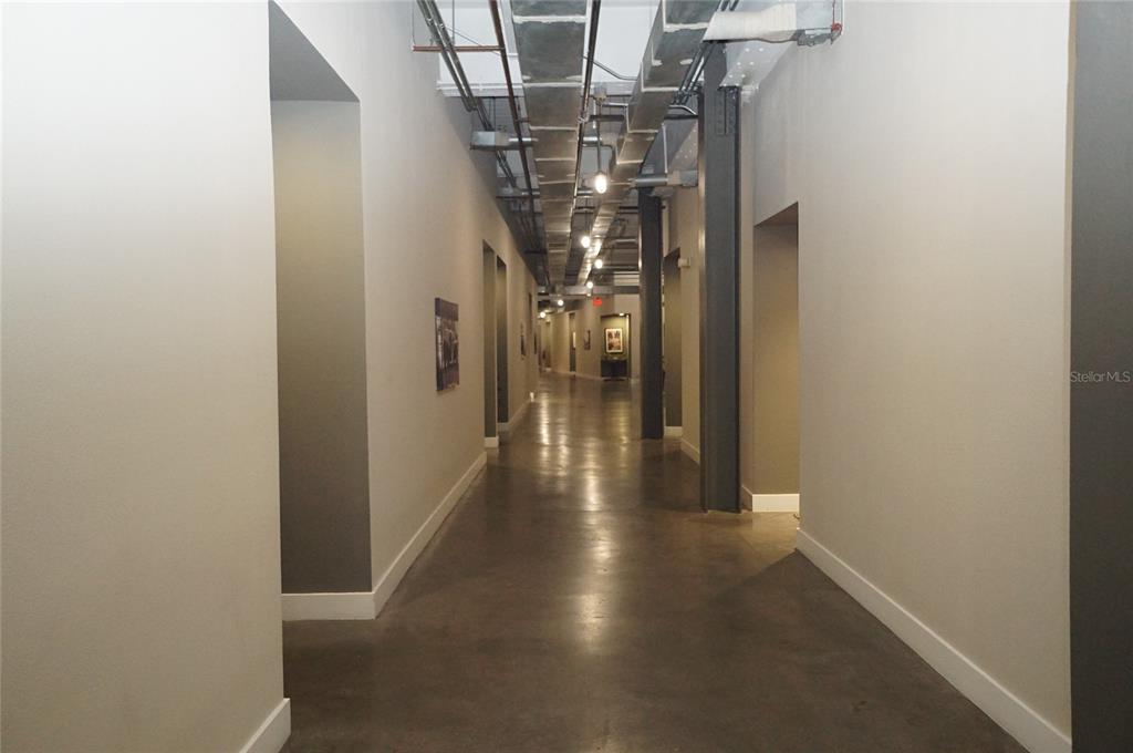 A long hallway features polished concrete floors, exposed industrial ductwork, and gray painted walls — 1501 W HORATIO STREET UNIT 111, TAMPA, FL