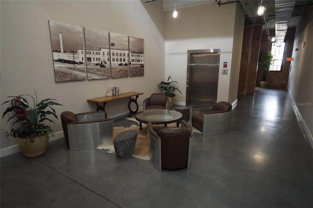 A lobby area features industrial-style metal and leather chairs, a glass coffee table, and wall art — 1501 W HORATIO STREET UNIT 111, TAMPA, FL