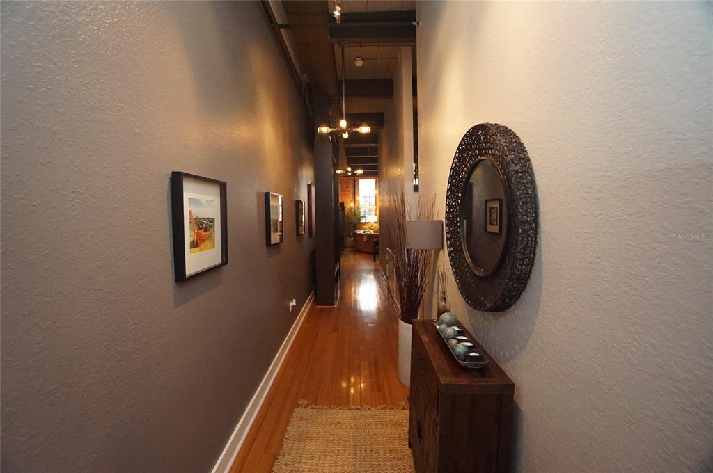 A long hallway features hardwood floors, dark gray walls, framed art, and a round mirror — 1501 W HORATIO STREET UNIT 111, TAMPA, FL