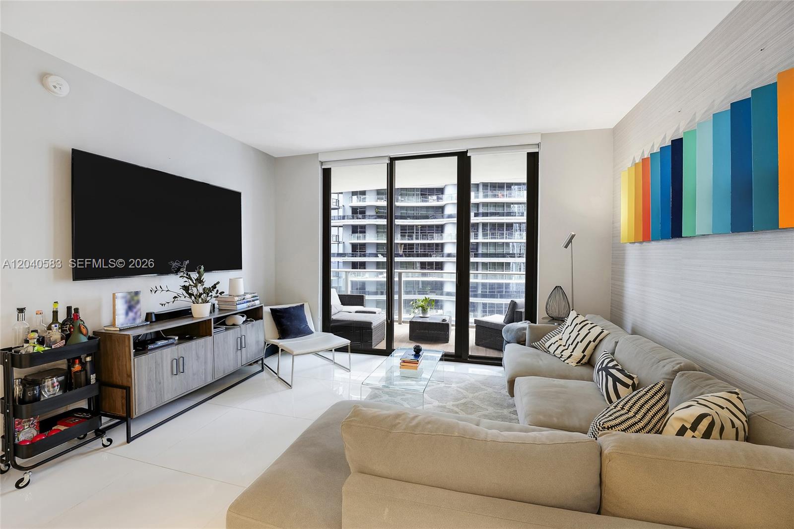 A living room features a gray sectional sofa, a media console, and a balcony view — 1010 Brickell Ave # 3007, Miami FL 33131, MIAMI, FL