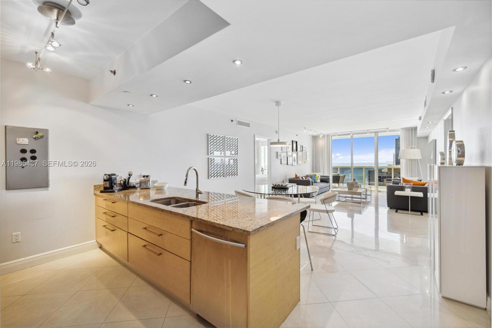 A kitchen island with granite countertops sits in an open-concept living space with ocean views — 1830 S Ocean Dr # 2703, Hallandale Beach FL 33009, HALLANDALE BEACH, FL