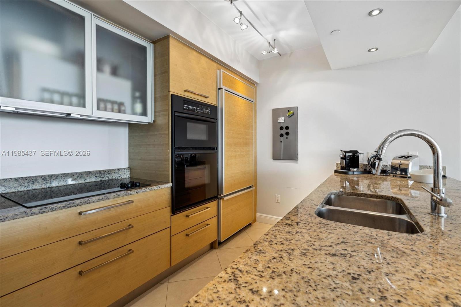 A kitchen features light wood cabinetry, granite countertops, stainless steel appliances, and a double sink — 1830 S Ocean Dr # 2703, Hallandale Beach FL 33009, HALLANDALE BEACH, FL