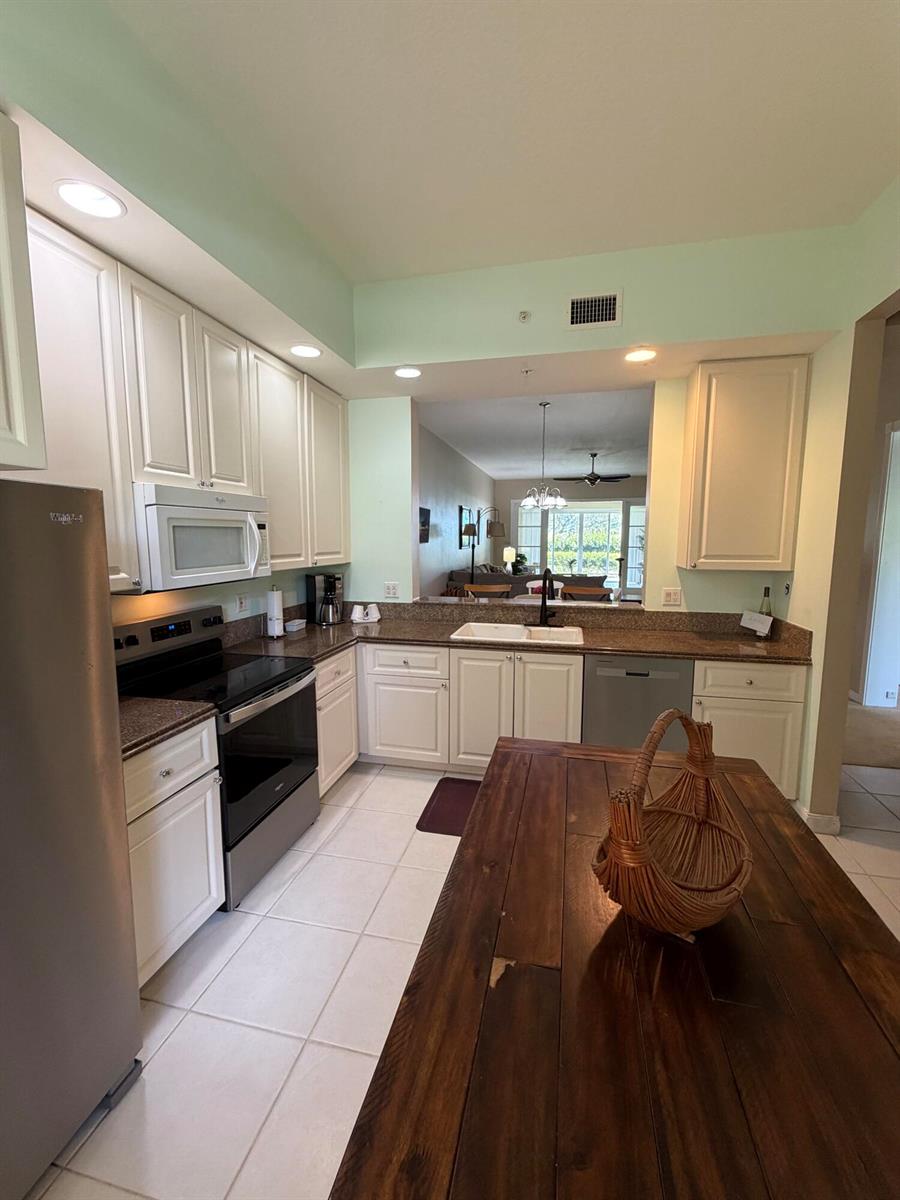 A kitchen features white cabinets, granite countertops, stainless steel appliances, and a wooden island — 38 E Harbour Isle Dr Drive E # 106, Fort Pierce FL 34949, FORT PIERCE, FL
