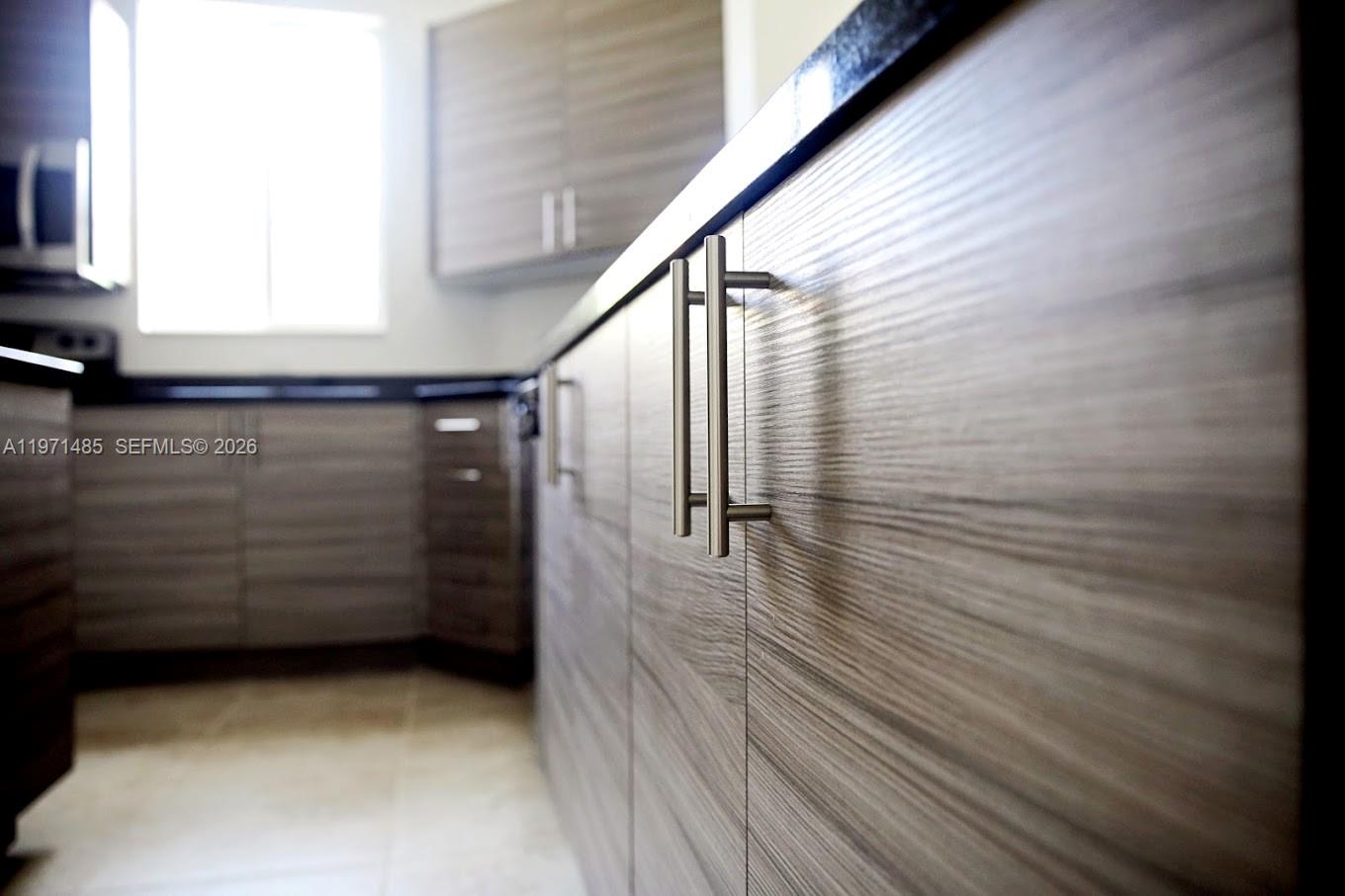 A kitchen features wood-grain cabinets with silver bar pulls and dark countertops — 2844 SW 81 # 2840, Miramar FL 33025, MIRAMAR, FL