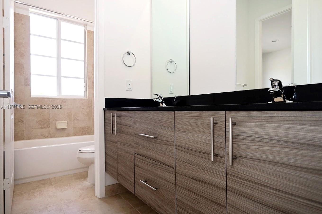 A bathroom features a wood-grain vanity with a black countertop and a tiled tub area — 2844 SW 81 # 2840, Miramar FL 33025, MIRAMAR, FL