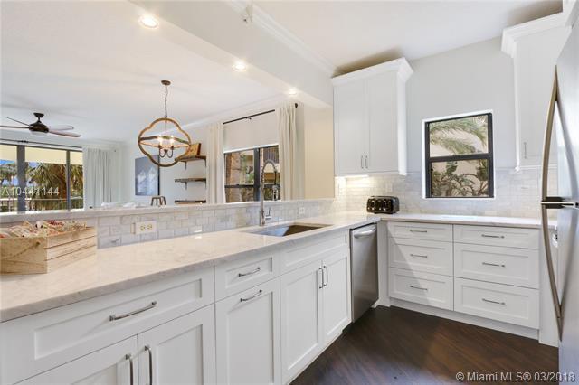 A kitchen with white cabinets, marble countertops, stainless steel appliances, and a view of palm trees — 100 Uno Lago Drive # 205, Juno Beach FL 33408, JUNO BEACH, FL