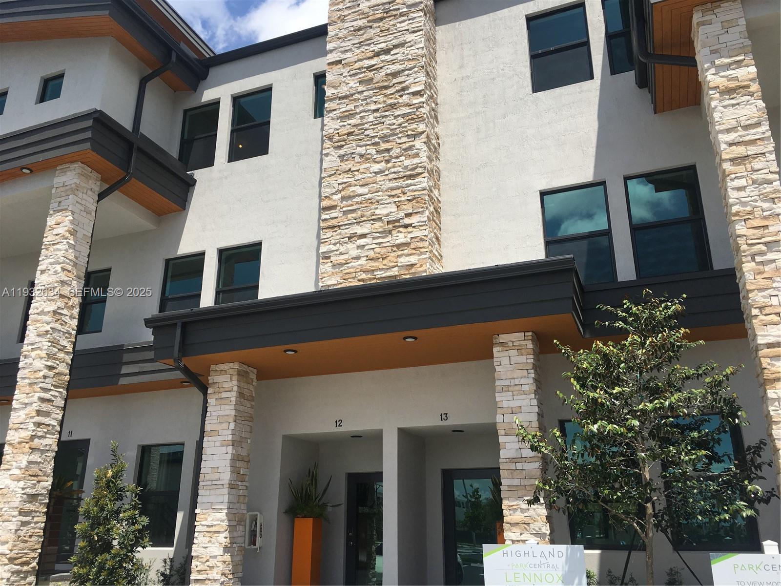 The exterior of a multi-story building features stone pillars, dark trim, and numbered entryways — 10461 NW 82nd St # 6, Doral FL 33178, DORAL, FL