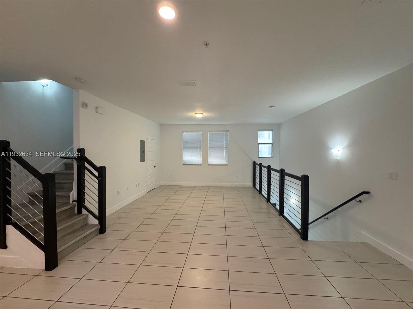 A spacious landing area features tiled flooring, a staircase with black railings, and white walls — 10461 NW 82nd St # 6, Doral FL 33178, DORAL, FL