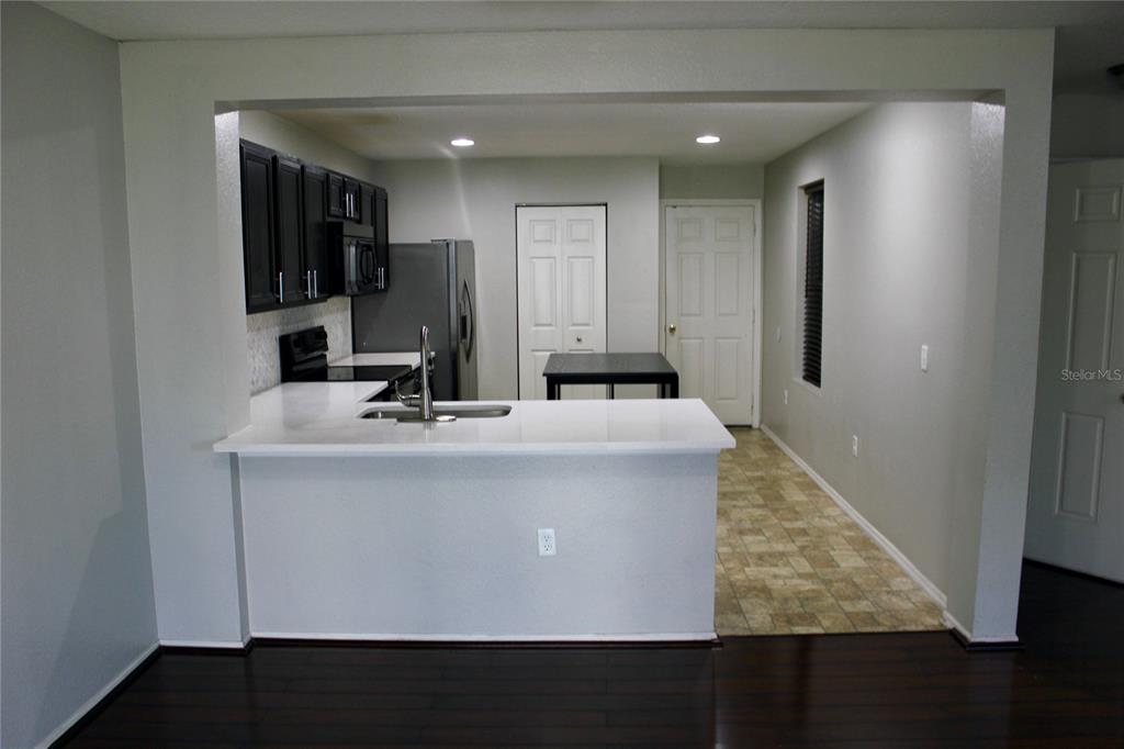 A kitchen features dark cabinets, white countertops, a breakfast bar, and a tiled floor — 1017 CHALCEDONY STREET, KISSIMMEE, FL