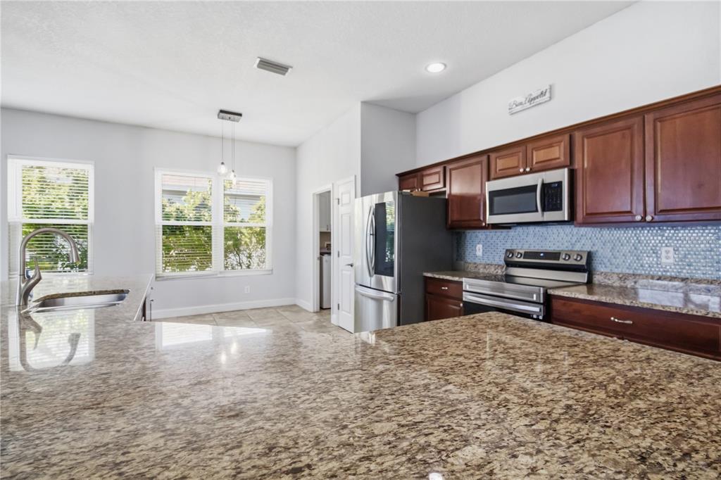 A kitchen features granite countertops, dark wood cabinets, stainless steel appliances, and a tiled backsplash — 5104 52ND AVENUE W, BRADENTON, FL