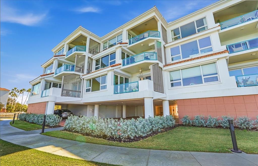 A multi-story residential building with balconies, large windows, and covered ground-level parking — 380 GULF OF MEXICO DRIVE UNIT 515, LONGBOAT KEY, FL