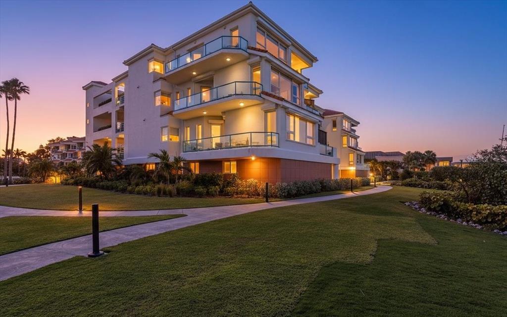 A multi-story residential building with balconies and exterior lighting at dusk — 380 GULF OF MEXICO DRIVE UNIT 515, LONGBOAT KEY, FL