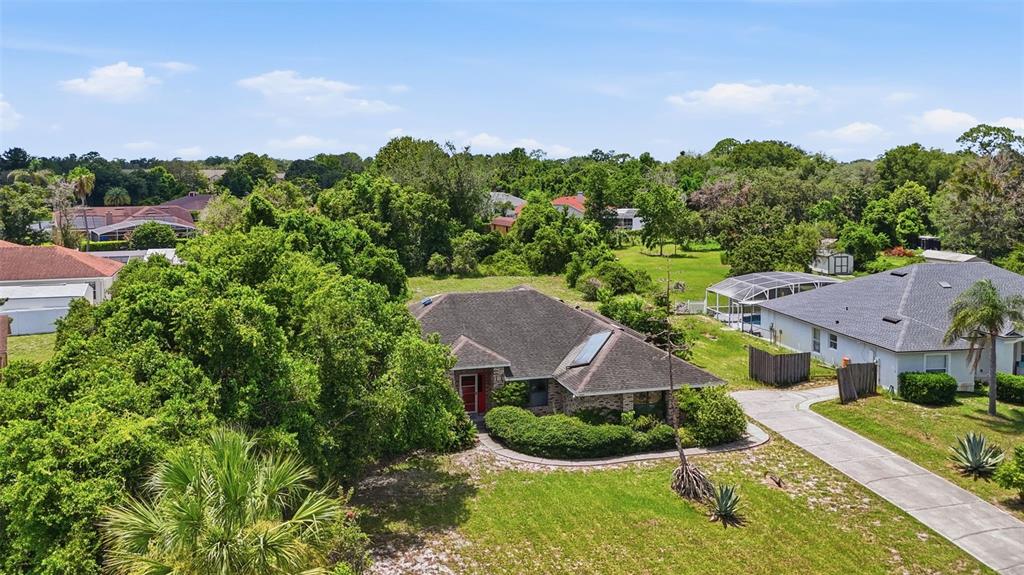 An aerial view shows a single-story house with a dark roof surrounded by lush trees — 3006 ANNEZ WAY, DEBARY, FL