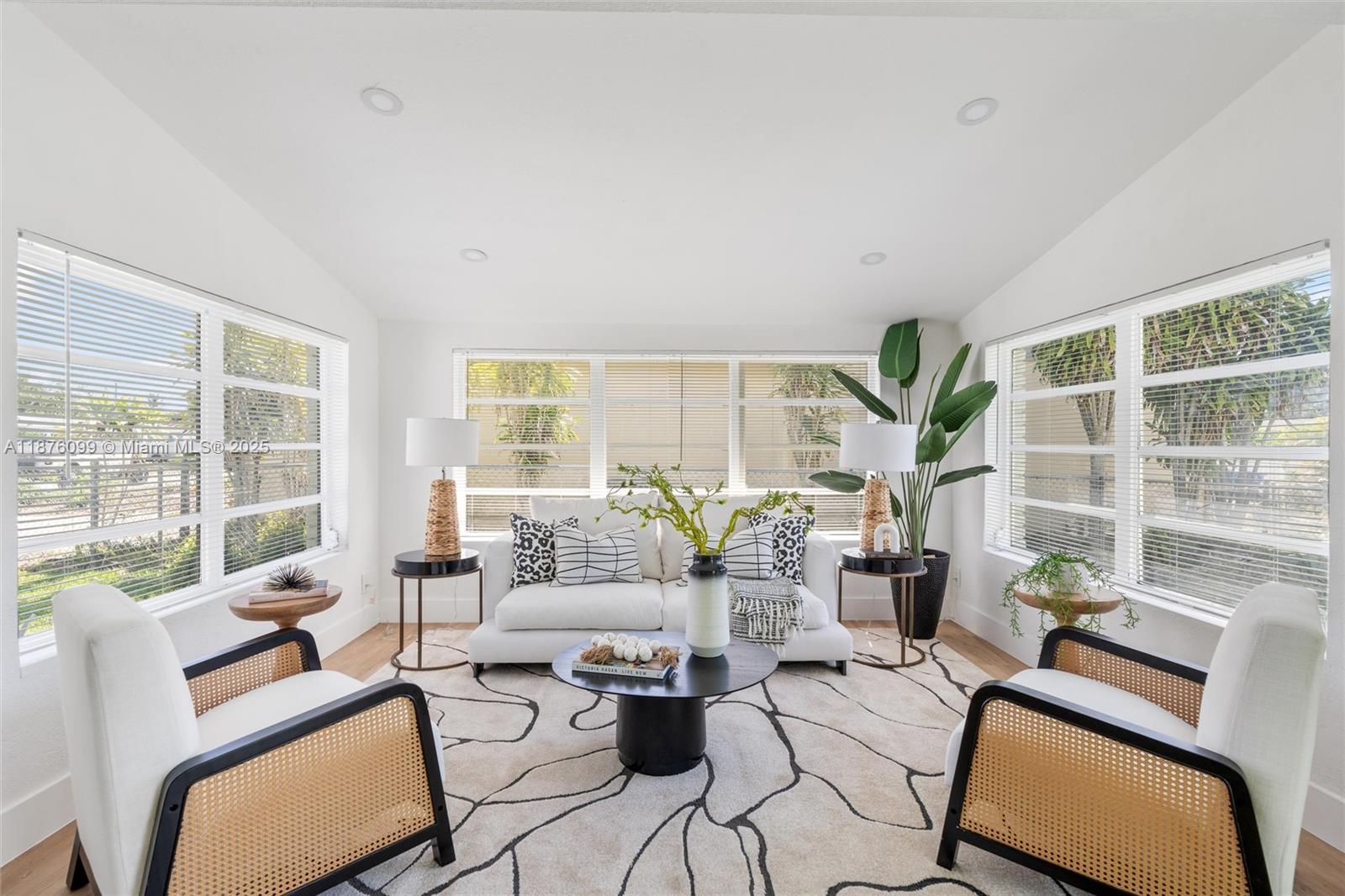 A bright living room features a white sofa, two cane chairs, and a patterned rug — 3230 Taft St, Hollywood FL 33021, HOLLYWOOD, FL
