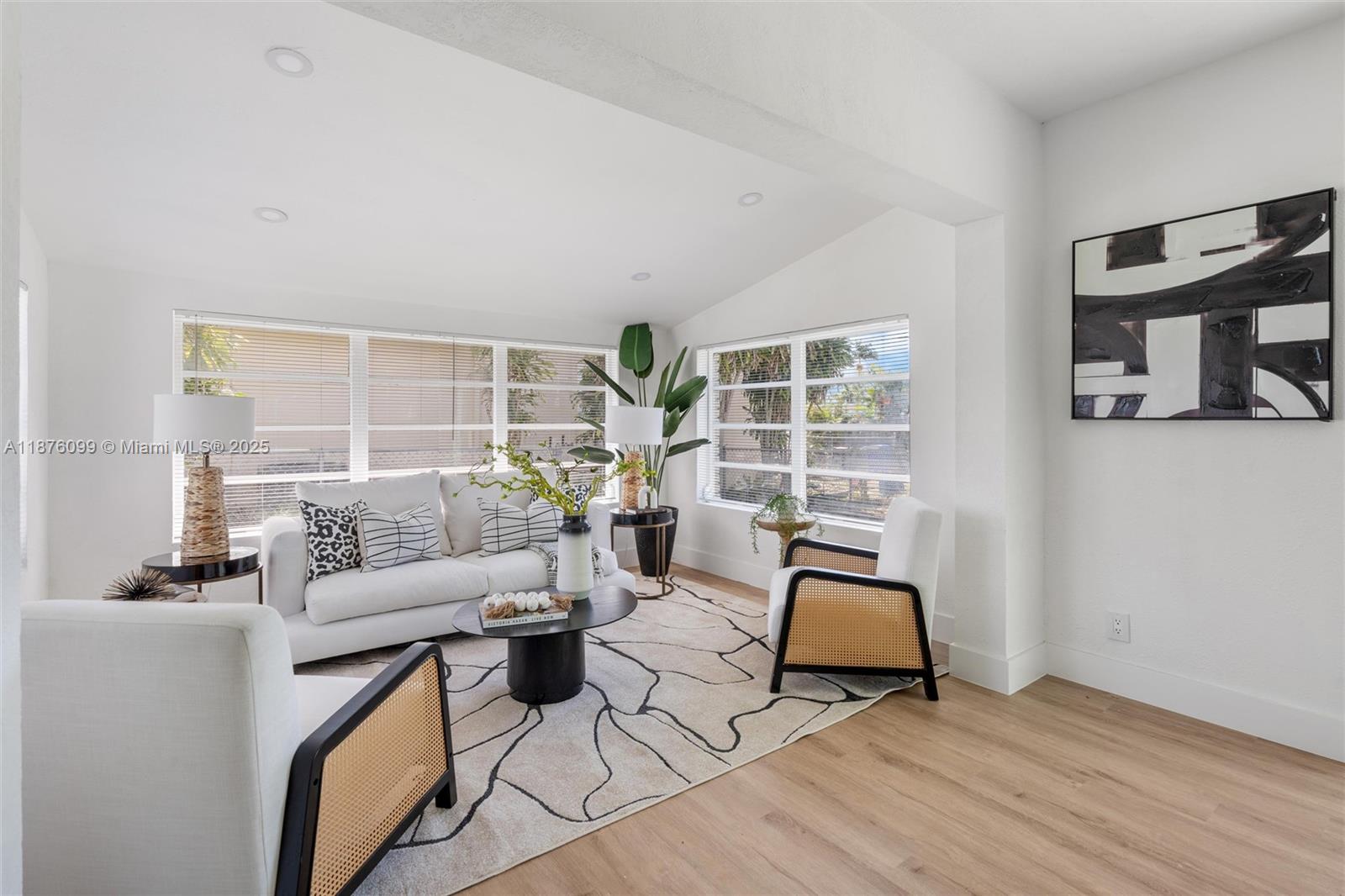 A bright living room features white walls, light wood flooring, and modern rattan-accented furniture — 3230 Taft St, Hollywood FL 33021, HOLLYWOOD, FL