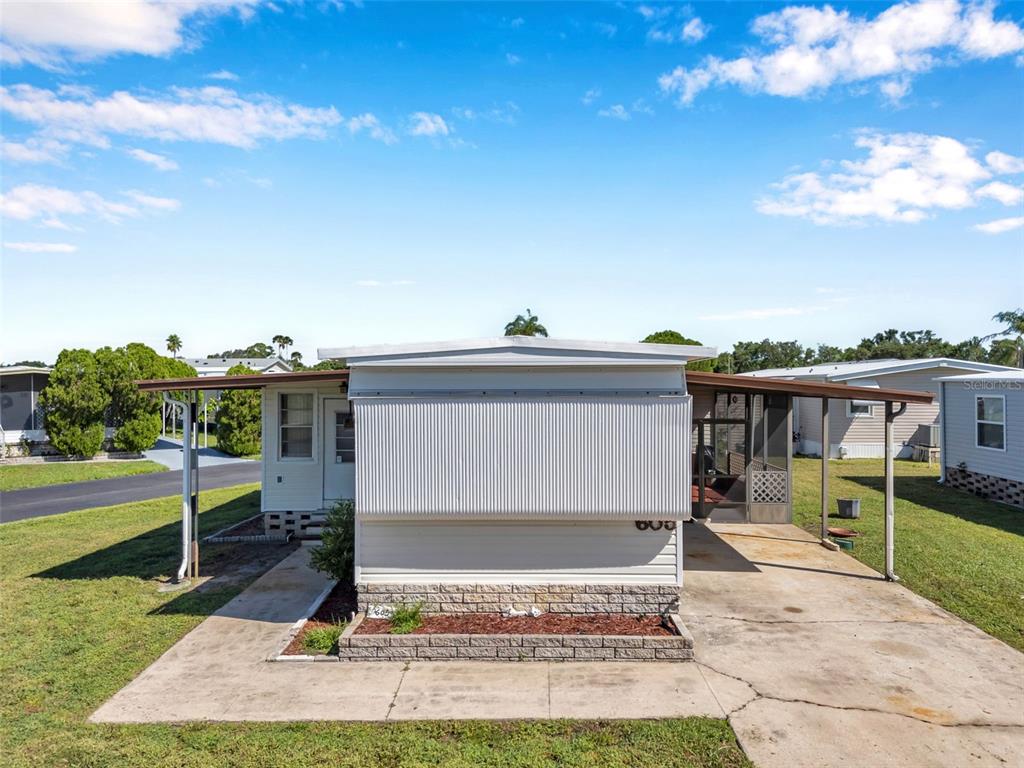A single-story mobile home features a concrete driveway, a carport, and a small brick planter — 605 MOUNT LANCASTER AVENUE NE UNIT 634, ST PETERSBURG, FL