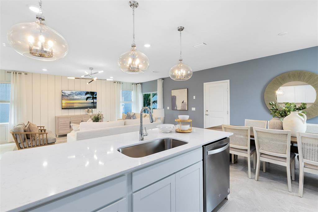 A kitchen island with a stainless steel sink overlooks an open-concept living and dining area — 6906 CREEK FALLS ALLEY, CLERMONT, FL
