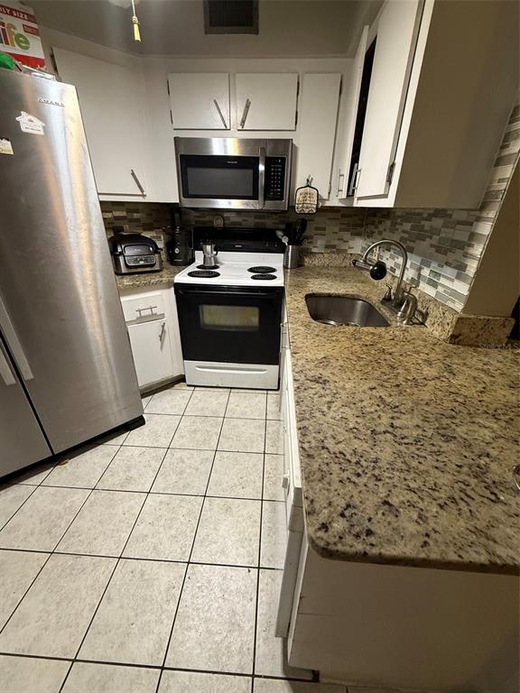 A kitchen features white cabinets, stainless steel appliances, granite countertops, and light-colored tile flooring — 3940 ATRIUM DRIVE UNIT L7, ORLANDO, FL