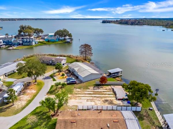 An aerial view shows a waterfront property with a house, a vacant lot, and docks — 1629 SUNSHINE LANE, TAVARES, FL