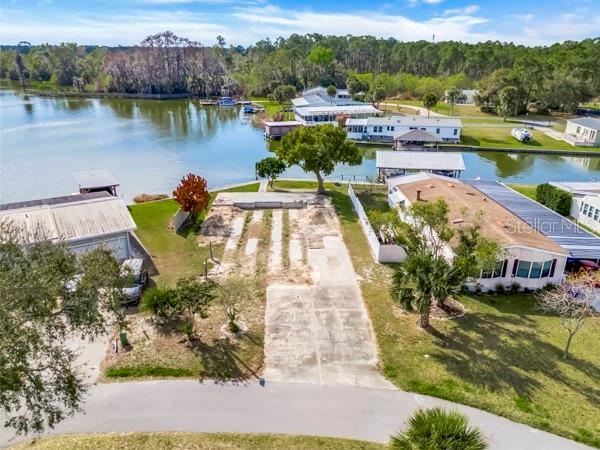 An aerial view shows a vacant waterfront lot situated between two mobile homes — 1629 SUNSHINE LANE, TAVARES, FL
