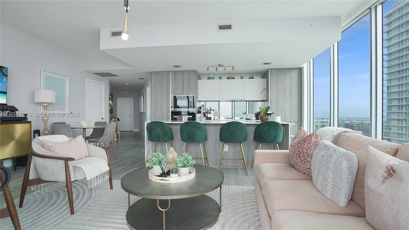 A modern open-concept living room and kitchen feature a pink sofa and green bar stools — 2900 NE 7th Ave # 4102, Miami FL 33137, MIAMI, FL