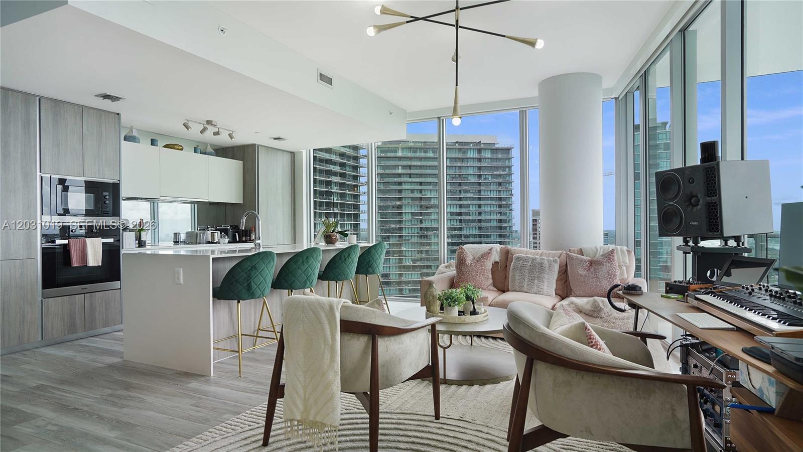A modern open-concept apartment features a kitchen with green bar stools and a living area — 2900 NE 7th Ave # 4102, Miami FL 33137, MIAMI, FL