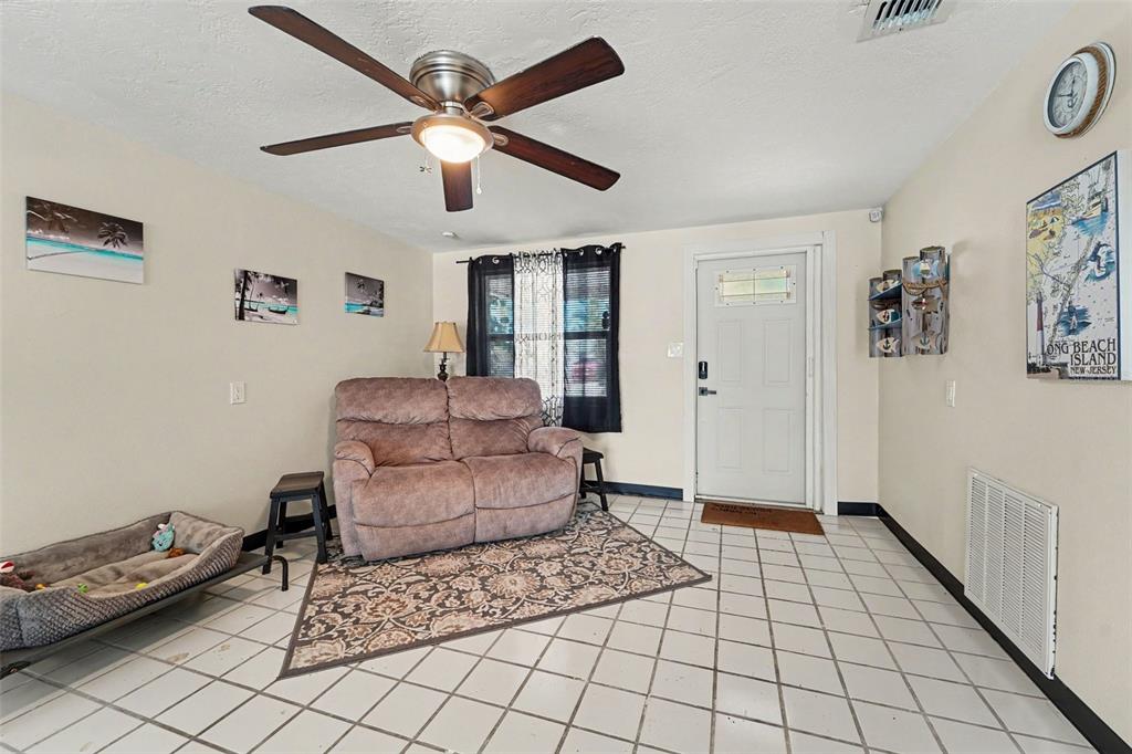 A living room features a brown loveseat, tiled floors, a ceiling fan, and wall decor — 13714 ALLYN DRIVE, HUDSON, FL