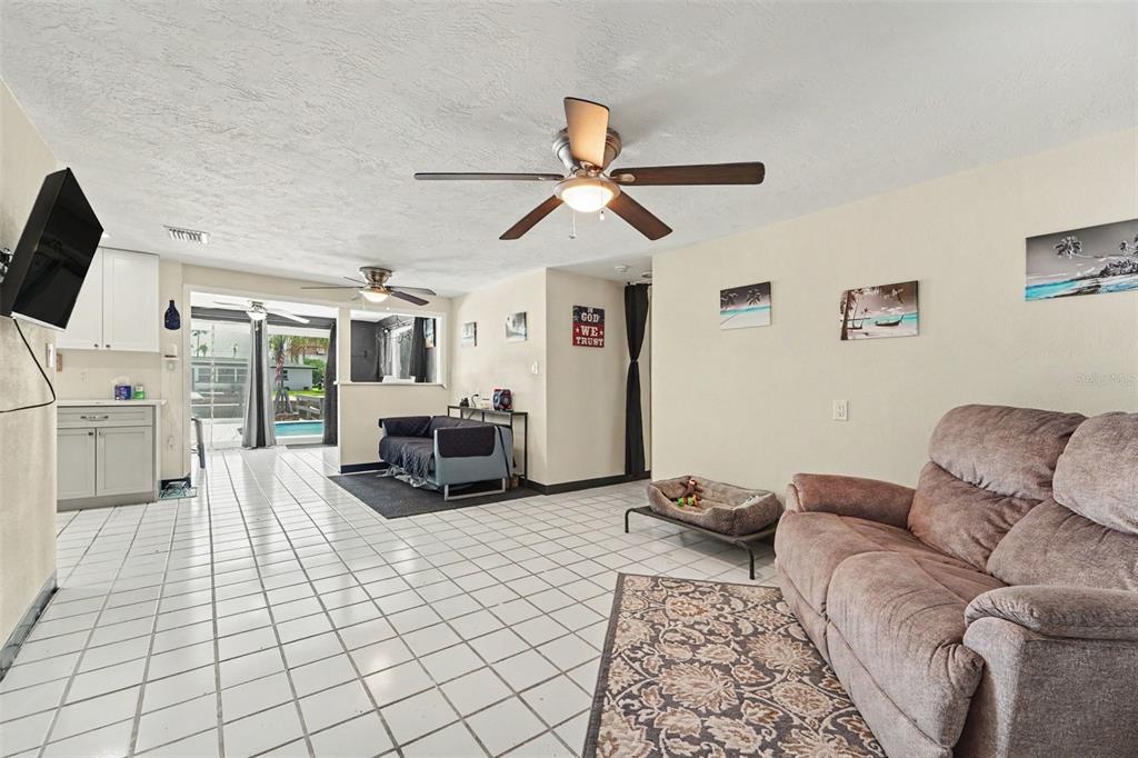 A living room with white tile floors, a brown sofa, and a ceiling fan — 13714 ALLYN DRIVE, HUDSON, FL