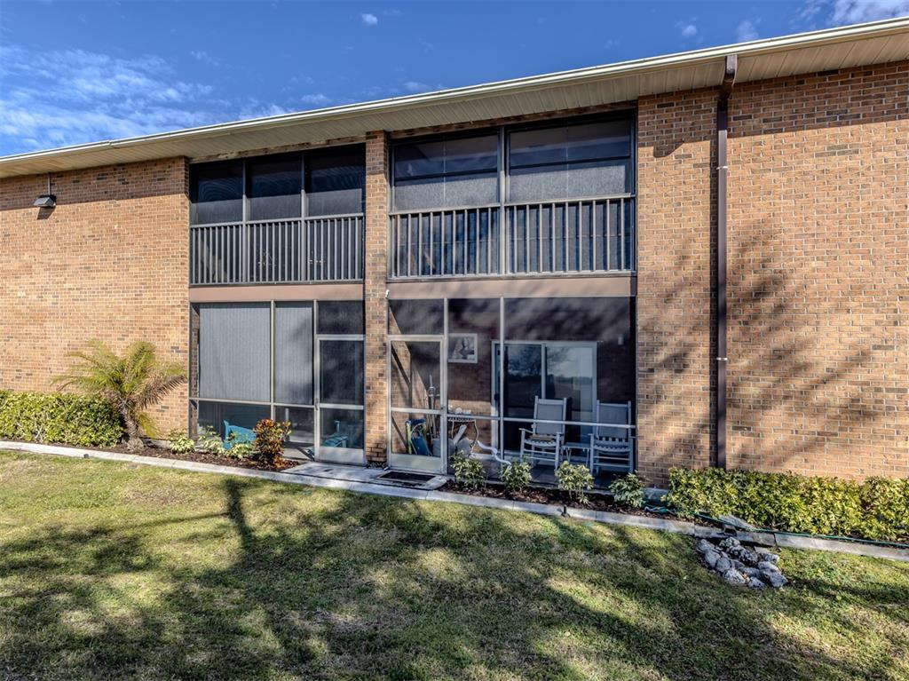 A two-story brick building features screened-in balconies and patios with sliding glass doors — 217 AIRPORT AVENUE W UNIT 216, VENICE, FL