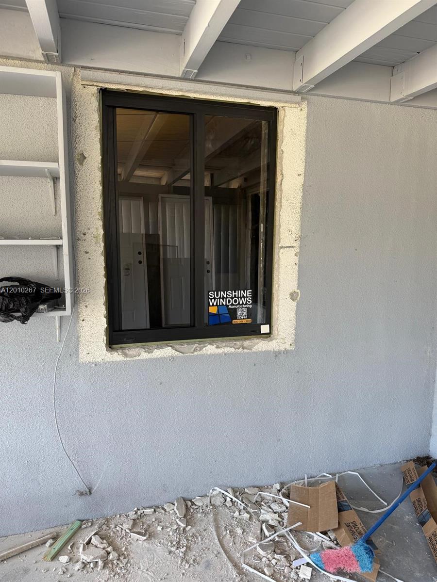 A newly installed window with exposed foam insulation sits in a gray stucco exterior wall — 1501 NW 3rd Way, Pompano Beach FL 33060, POMPANO BEACH, FL