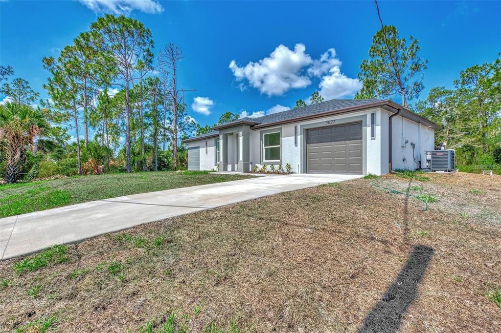 A single-story house with a gray garage, white stucco walls, and a concrete driveway — 4637 CORBETT LANE, NORTH PORT, FL