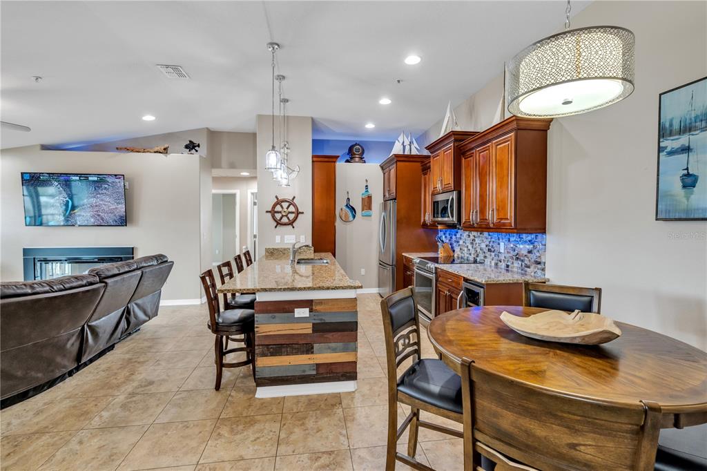A kitchen with wood cabinets, granite countertops, and a rustic wood-paneled island — 6420 BANYAN BOULEVARD UNIT 303, NEW PORT RICHEY, FL