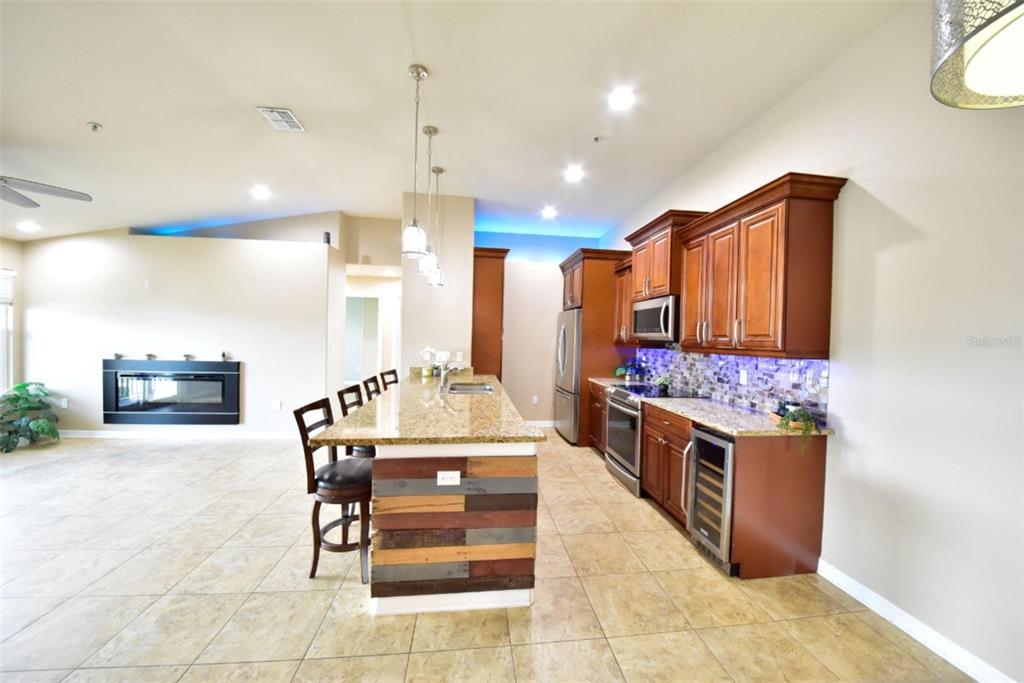 A kitchen with wood cabinets, granite countertops, a reclaimed wood island, and tile flooring — 6420 BANYAN BOULEVARD UNIT 303, NEW PORT RICHEY, FL