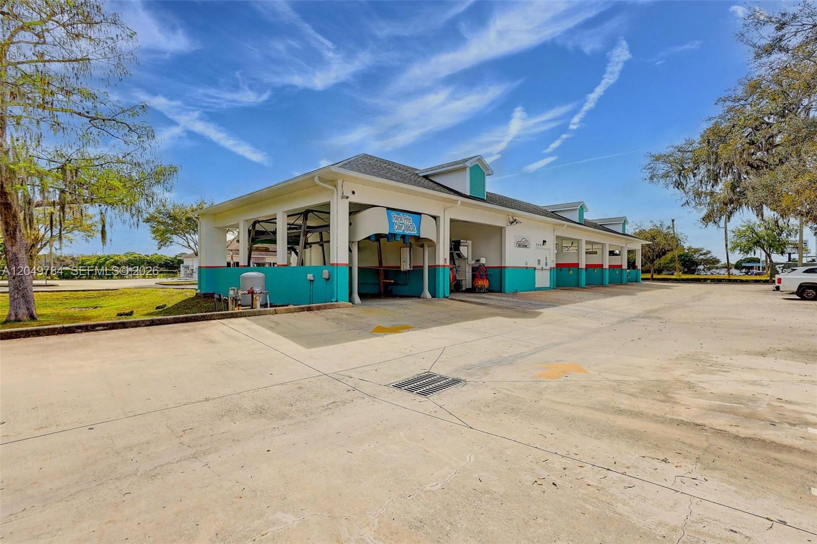 An exterior view of a multi-bay car wash facility with teal and white painted walls — 3901 Orange Ave, Fort Pierce FL 34947, FORT PIERCE, FL