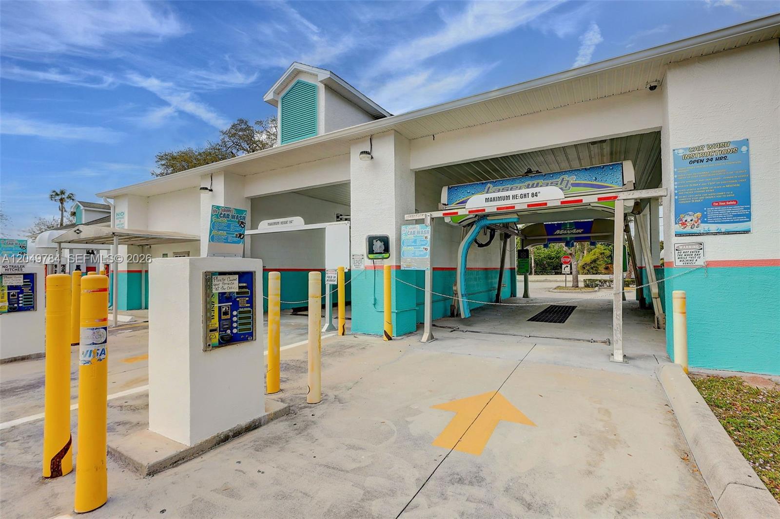 An exterior view of a drive-through car wash facility with yellow bollards and signage — 3901 Orange Ave, Fort Pierce FL 34947, FORT PIERCE, FL
