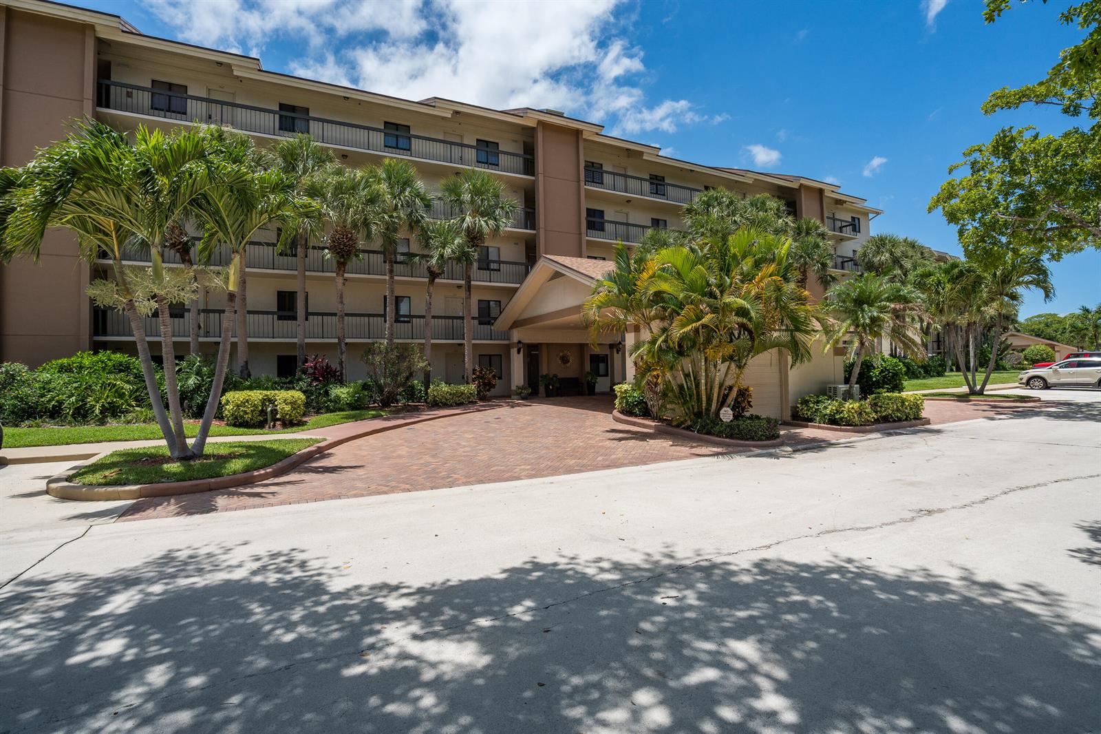 A multi-story apartment building features a brick driveway leading to a covered entrance with palm trees — 901 Seafarer Circle # 306, Jupiter FL 33477, JUPITER, FL