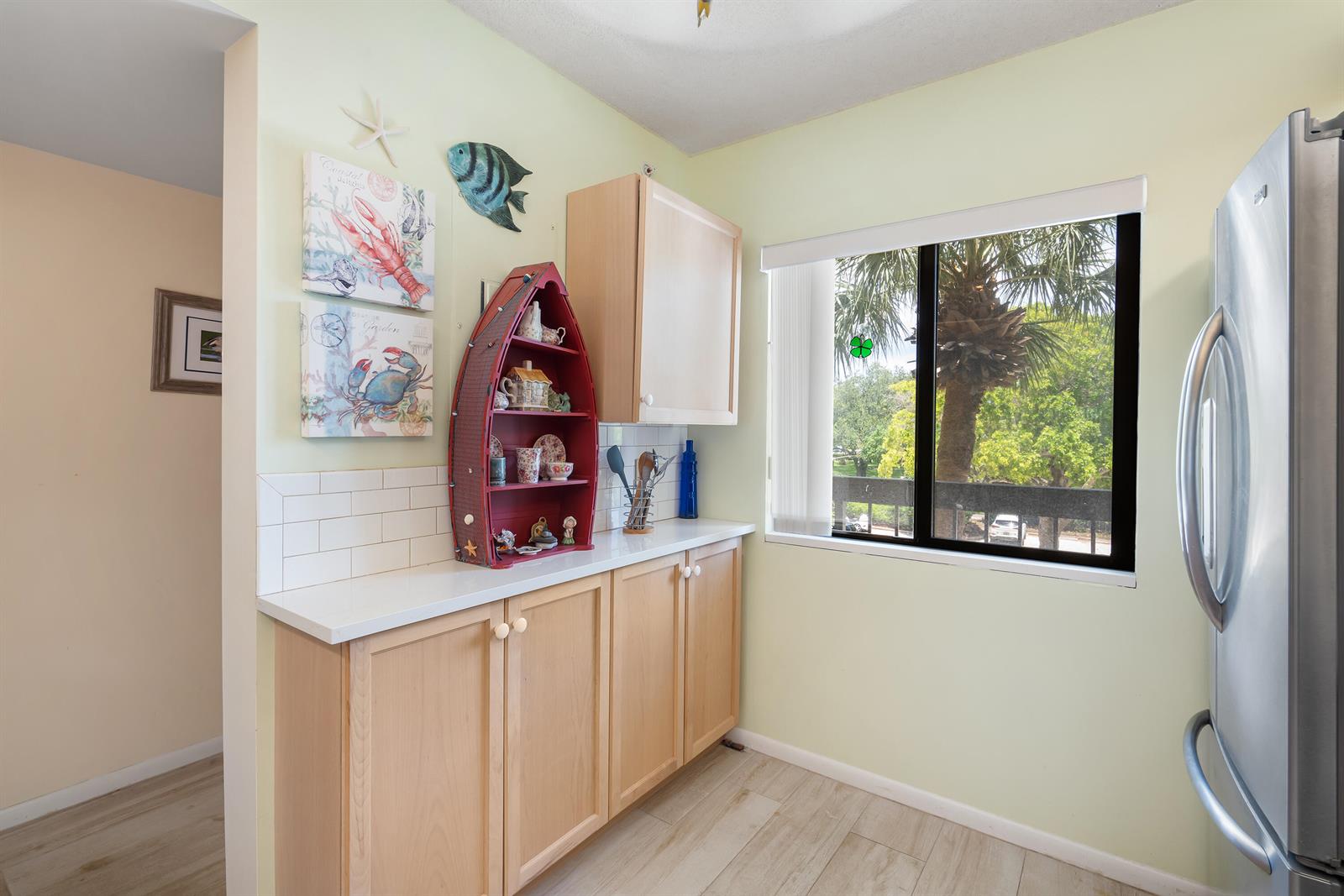 A kitchen area features light wood cabinets, white countertops, a red boat-shaped shelf, and a window — 901 Seafarer Circle # 306, Jupiter FL 33477, JUPITER, FL