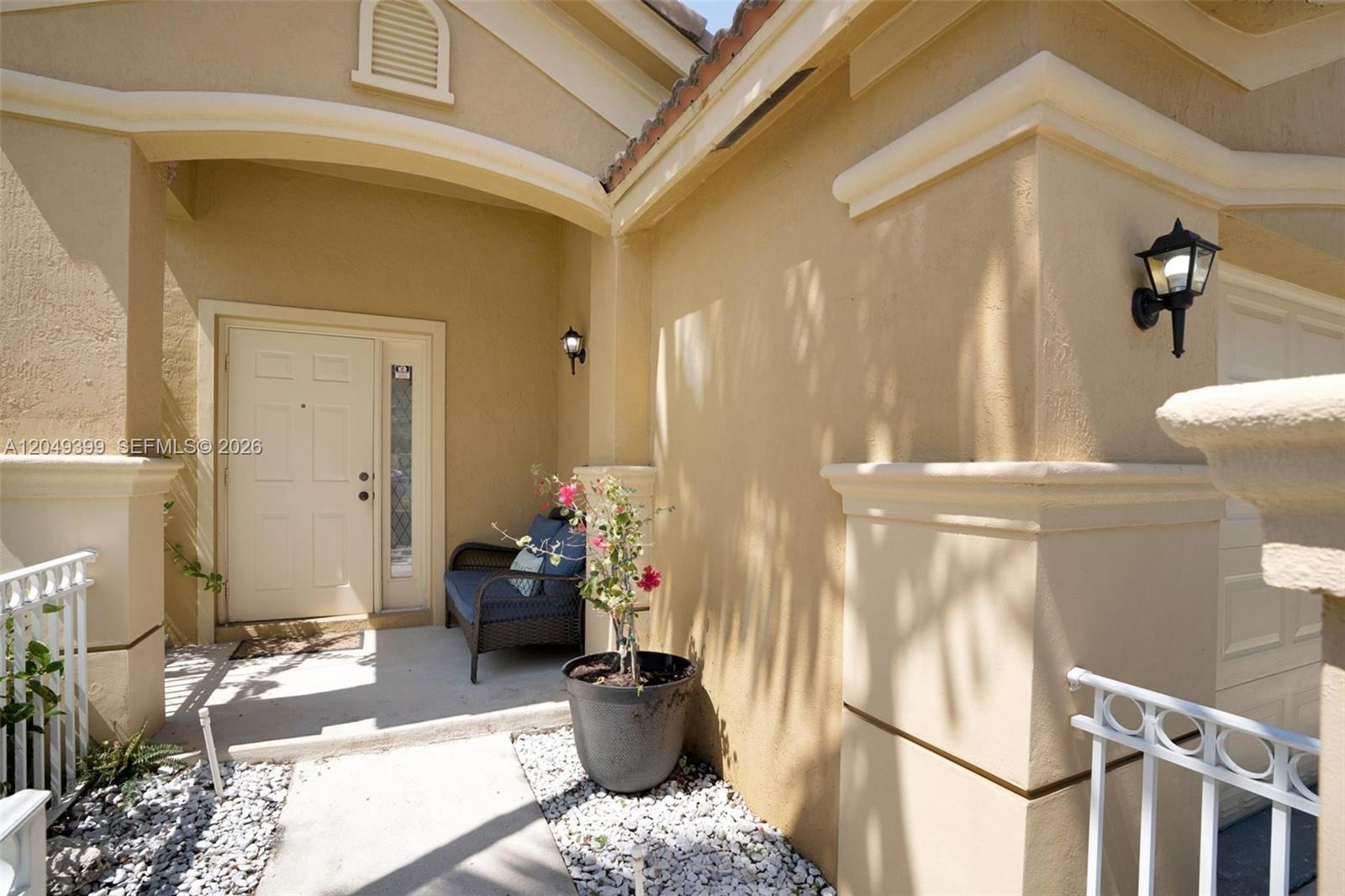 The exterior entrance features a beige stucco facade, a front door, and a small bench — 899 Phoenix Way, Weston FL 33327, WESTON, FL