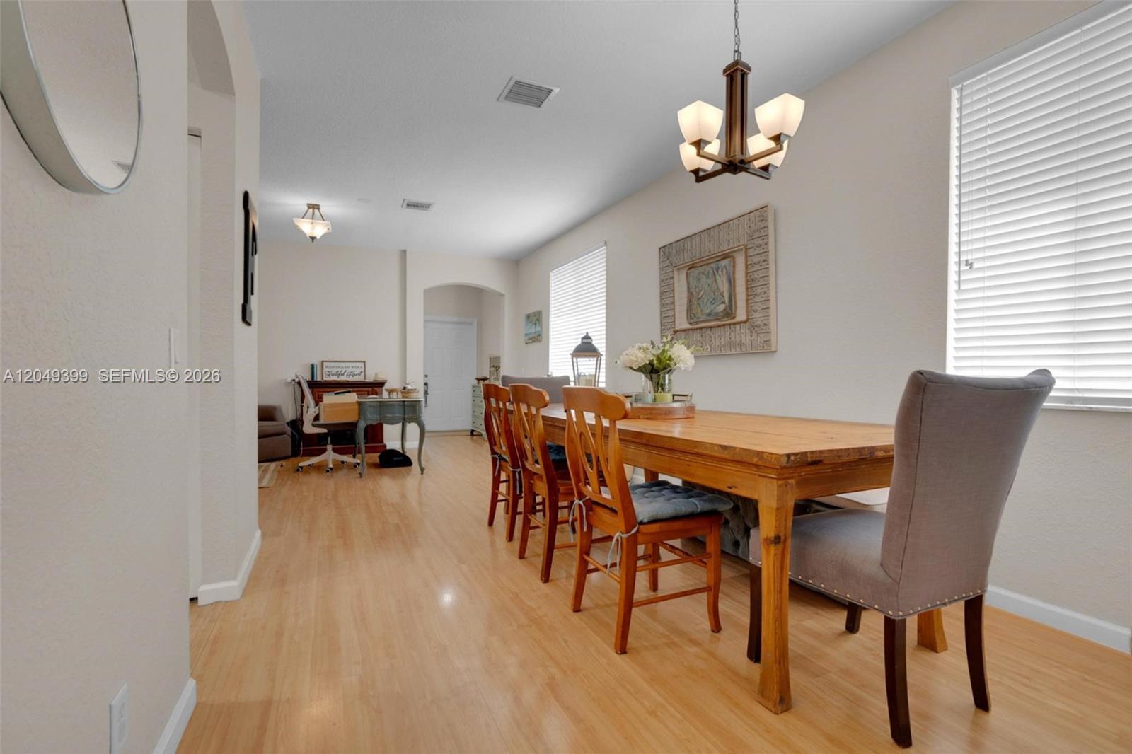 A dining room features a wooden table with mixed seating and light wood flooring — 899 Phoenix Way, Weston FL 33327, WESTON, FL