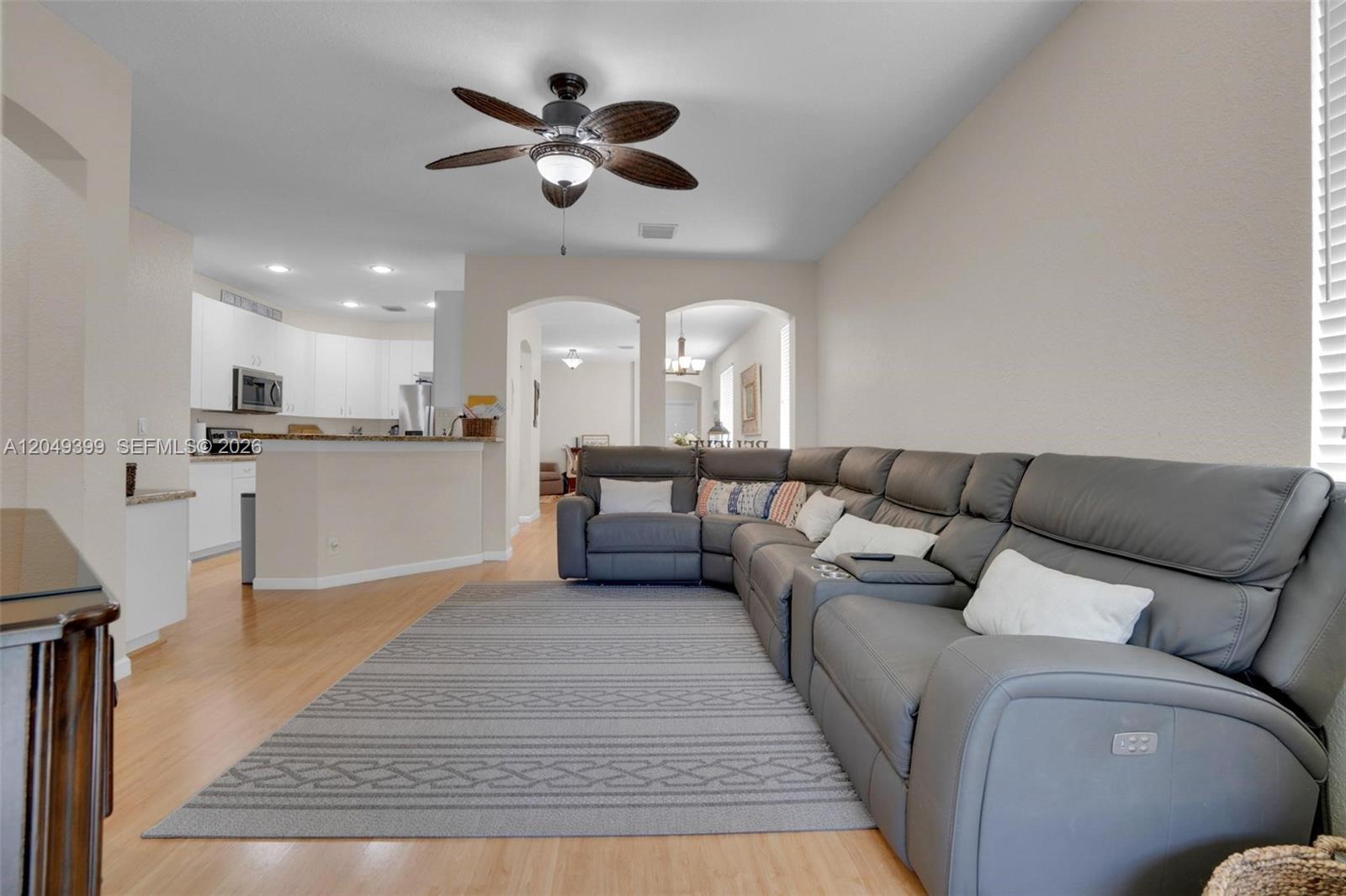 A living room features a large gray sectional sofa, a patterned area rug, and wood flooring — 899 Phoenix Way, Weston FL 33327, WESTON, FL