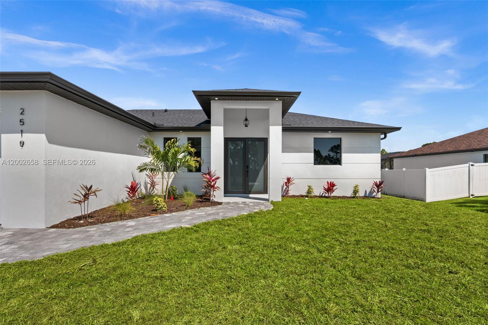 A modern white house features a dark roof, double front doors, and a paved walkway — 2519 NW 18TH, Cape Coral FL 33993, CAPE CORAL, FL