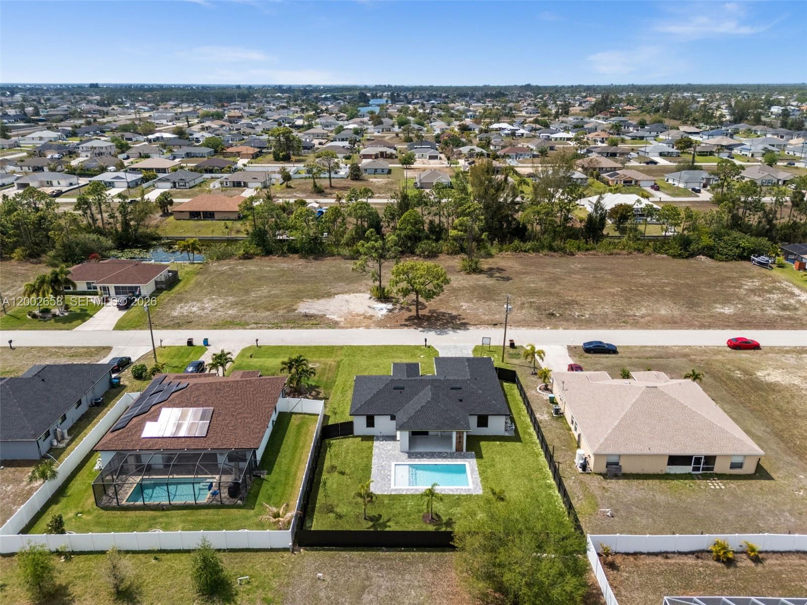 An aerial view shows three suburban houses with swimming pools and fenced backyards — 2519 NW 18TH, Cape Coral FL 33993, CAPE CORAL, FL