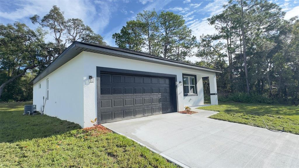A white single-story house with a black garage door and a concrete driveway — 2827 W XENOX DRIVE, CITRUS SPRINGS, FL