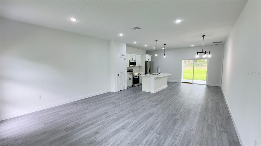 An open-concept kitchen and living area features white cabinetry, a center island, and gray flooring — 2827 W XENOX DRIVE, CITRUS SPRINGS, FL